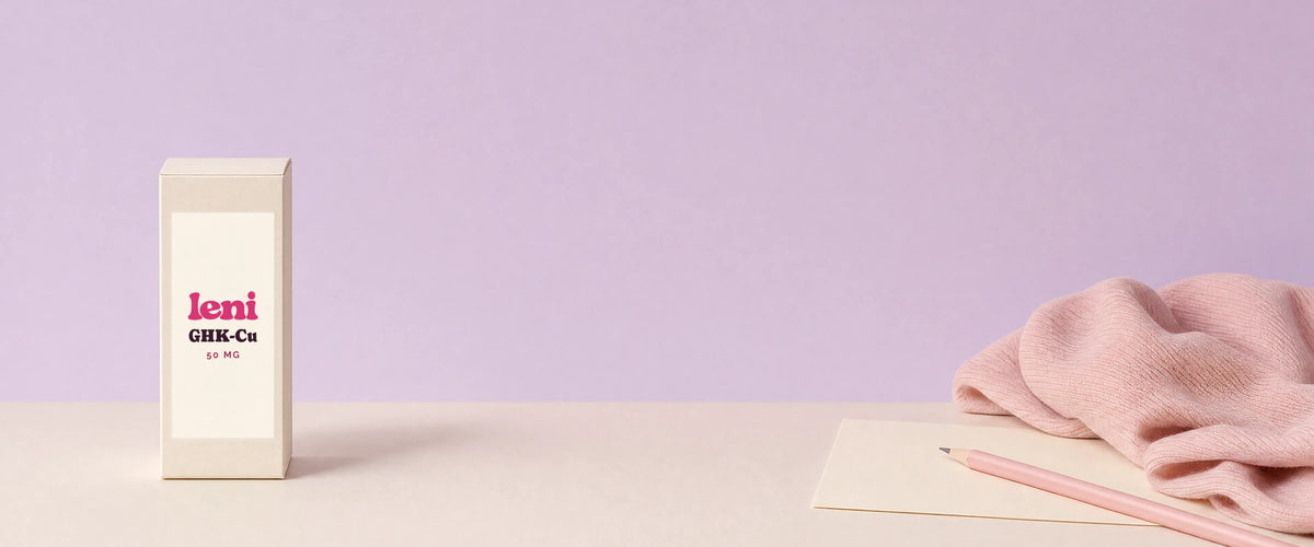 A Leni carton, a blank note card and a pink pencil on a cream surface against a lilac wall.