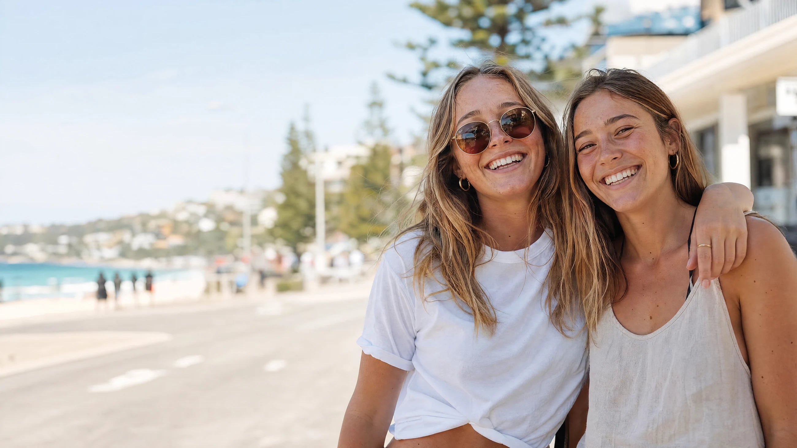 Two women smiling together beside Bondi Beach